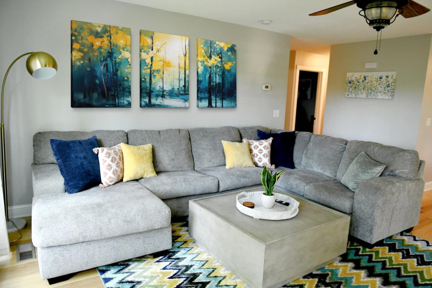 Grey sectional and forest paintings