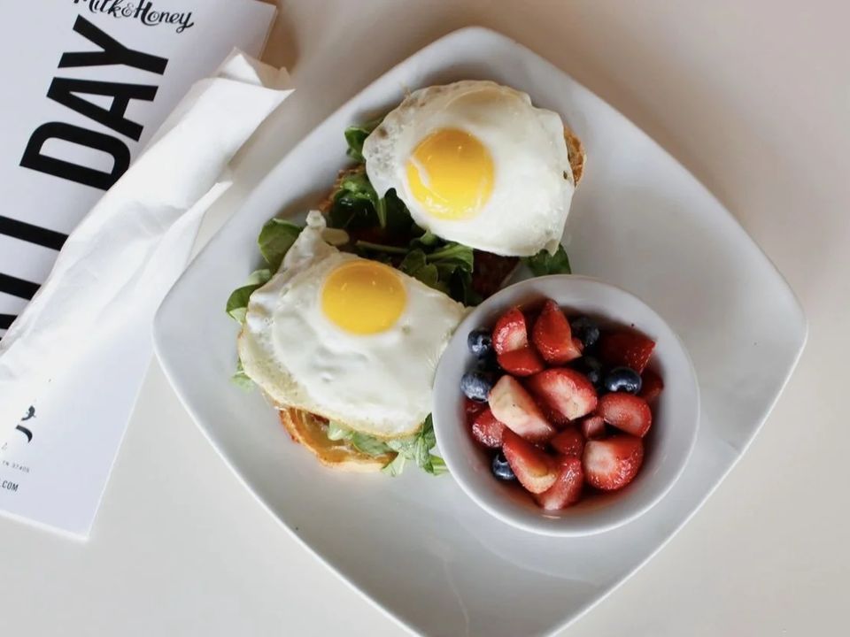 Two fried eggs on toast with a side of strawberries