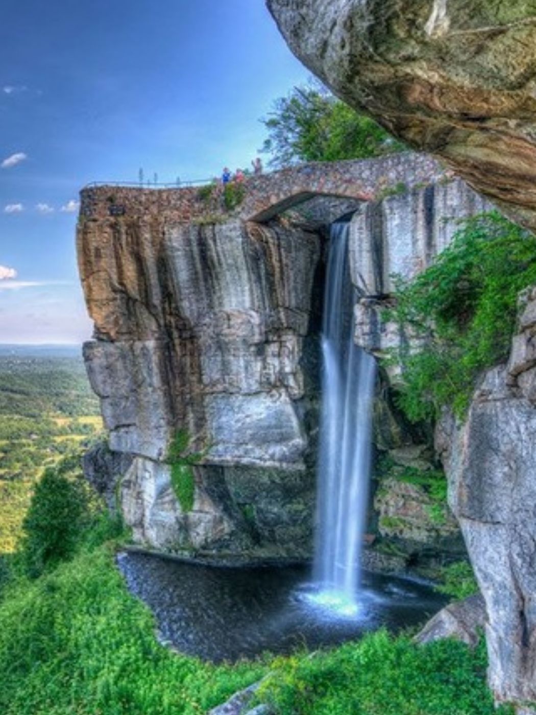 Waterfall pouring off a rock cliff at Rock City with farmland below